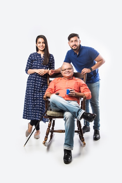 Indian old man or father with young son and daughter, sitting over rocking chair