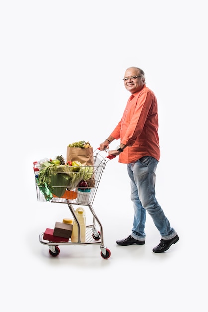 ショッピングカートまたは野菜、果物、食料品でいっぱいのトロリーを持つインドの老人