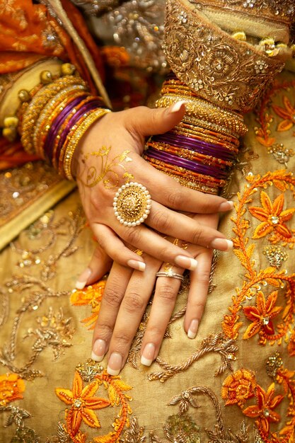 Indian pakistani bride hands with bracelets ring and golden henna tattoo close up