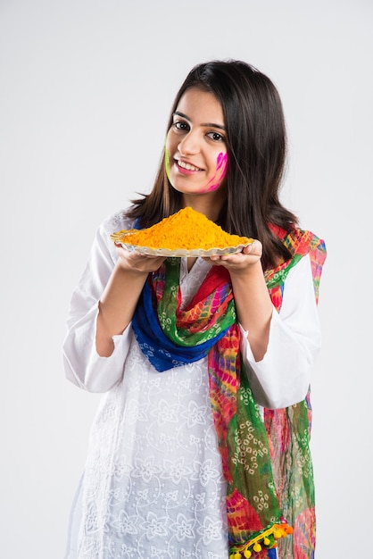 Indian people celebrating holi with sweet laddu, colours in thali and colour splash