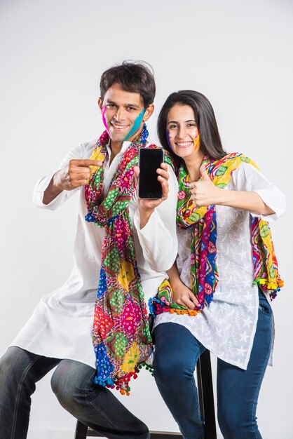 Indian people celebrating holi with sweet laddu, colours in thali and colour splash