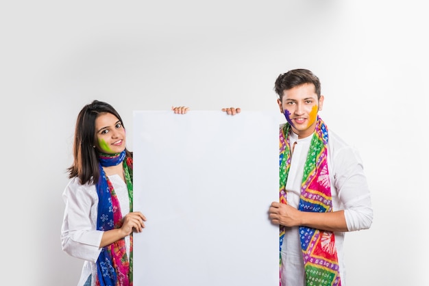 Indian people celebrating holi with sweet laddu, colours in thali and colour splash