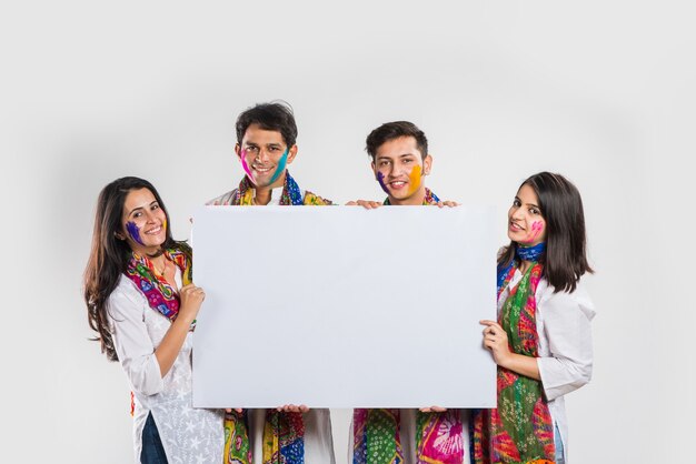 Indian people celebrating holi with sweet laddu, colours in thali and colour splash