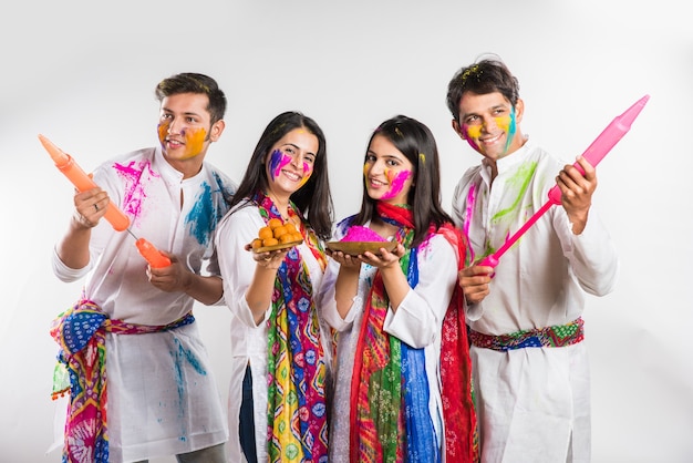 Indian people celebrating holi with sweet laddu, colours in thali and colour splash