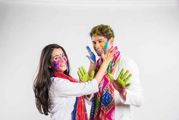 Indian people celebrating holi with sweet laddu, colours in thali and colour splash