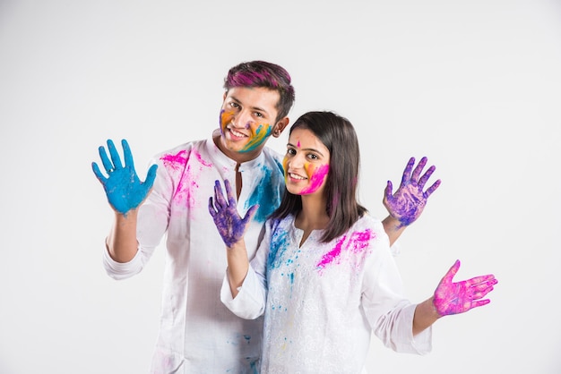 Indian people celebrating holi with sweet laddu, colours in thali and colour splash