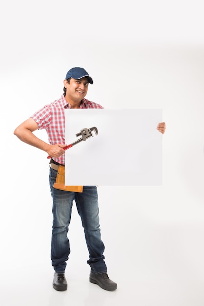 Indian plumber holding drawing roll and Pipe wrench or plumbing spanner or smartphone, standing isolated