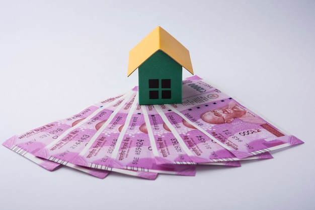 Indian Real estate business concept showing 3D model house with keys, paper currency notes and Calculator. Selective focus