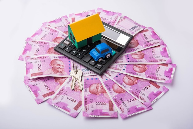 Indian Real estate business concept showing 3D model house with keys, paper currency notes and Calculator. Selective focus