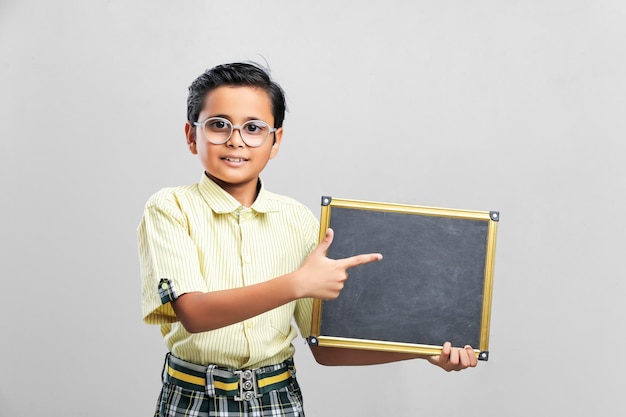 Indian school boy showing black board with copy space