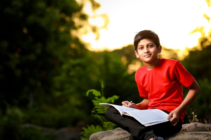 फोटो indian school boy with note book and studying at home
