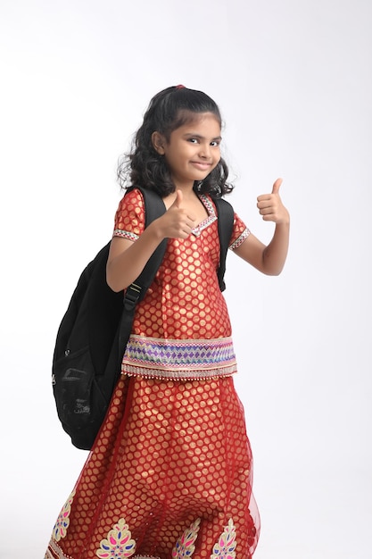 Indian school girl showing thumps up on white background