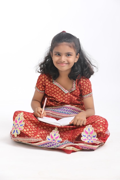 Indian school girl studying on white background