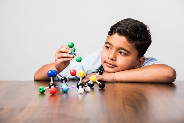 Indian school kid or science student Using Molecular Model Kit for studying physics, selective focus
