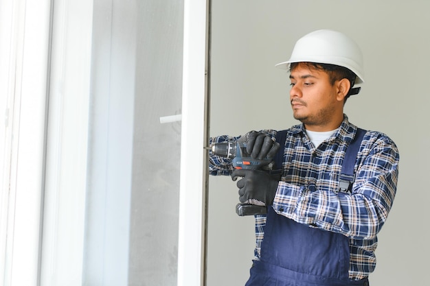 Indian service man installing window with screwdriver