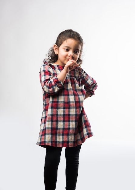 Indian small girl asks to keep silence or quiet with index finger on her mouth