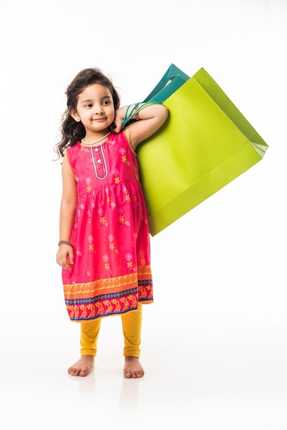 Indian small girl holding shopping bags, standing isolated over white background