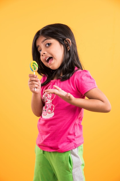 Indian small girl with lolipop or loly pop, asian girl and lolipop or lolypop, playful indian cute girl posing with lolipop or candy