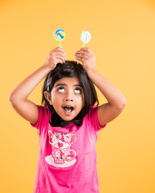 Indian small girl with lolipop or loly pop, asian girl and lolipop or lolypop, playful indian cute girl posing with lolipop or candy