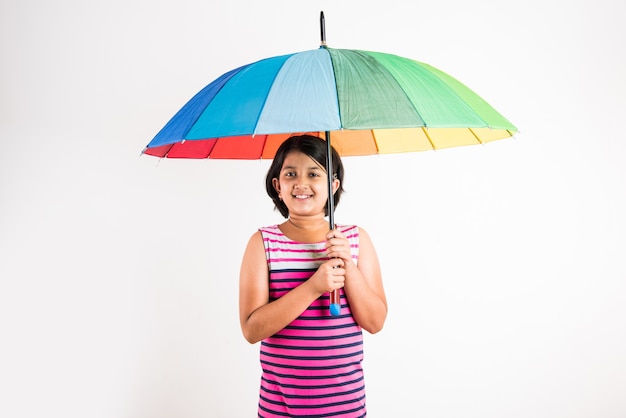 Indian small girl with multicolored umbrella, isolated over white