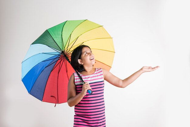 Piccola ragazza indiana con ombrello multicolore, isolata su bianco