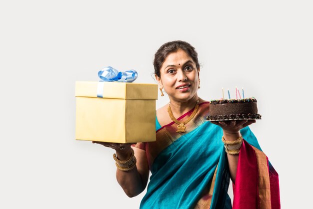 Indian smart old lady celebrating birthday alone with cake while wearing designer saree &amp; jewellery