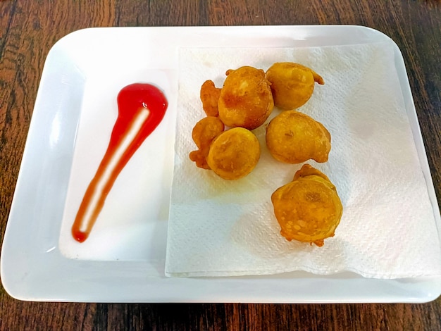 Indian snack pakora with sauce on wooden background with copy space