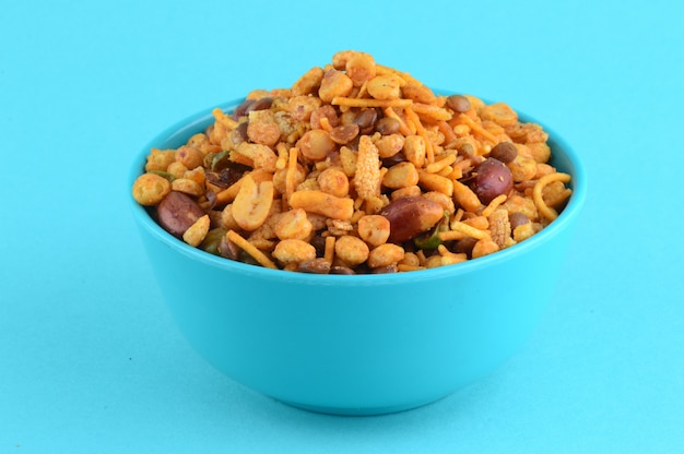 Индийские закуски: смесь (жареные орехи с солью, перцем масала, бобовые, зелёный горошек чанна масала дал) в синей миске в