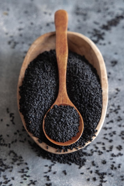 Indian spice Black cumin nigella sativa or kalonji seeds in bowl with spoon on wooden table top view