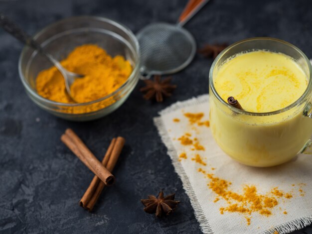 Indian spice turmeric Golden milk in a mug on a dark stone table