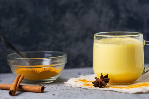 Indian spice turmeric Golden milk in a mug on a dark stone table