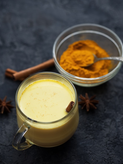 Curcuma spezia indiana latte dorato in una tazza su un tavolo di pietra scura