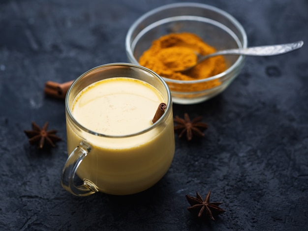 Indian spice turmeric Golden milk in a mug on a dark stone table