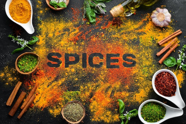 Indian spices on a black stone background. The word "spice" Indian spices. Top view.