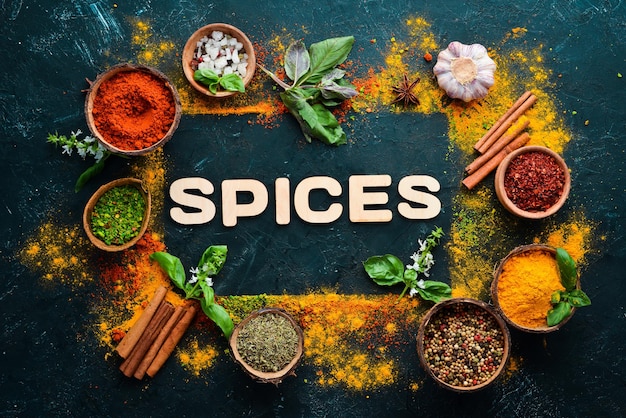 Indian spices on a black stone background. The word "spice" Indian spices. Top view.