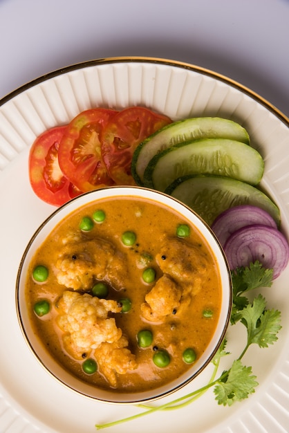 Foto cibo piccante indiano gobi masala o curry di cavolfiore con piselli verdi, servito in una ciotola di ceramica, fuoco selettivo