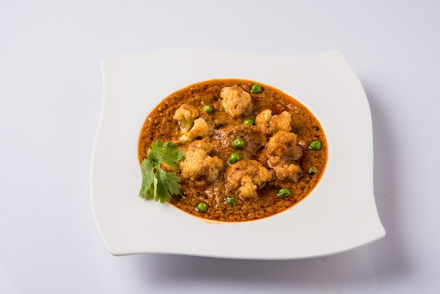 Indian spicy food Gobi Masala or cauliflower curry with green peas, served in a ceramic bowl, selective focus