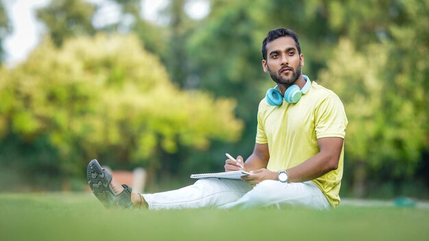 草の上に座って何かを考えているインドの学生