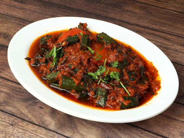 Indian style Bhindi masala or Okra curry also known as Ladyfinger served over a rustic wooden table selective focus