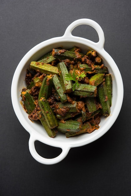 Stile indiano masala sabji o sabzi di bhindi fritto o okra noto anche come ladyfinger, servito in una ciotola su sfondo lunatico. messa a fuoco selettiva