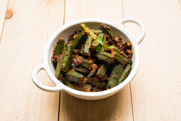 Indian style Masala Sabji OR Sabzi of fried Bhindi OR Okra also known as Ladyfinger, Served in a bowl over moody background. selective focus