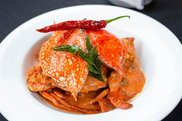 Foto curry di granchio salato in stile indiano con peperoncino rosso e foglia verde servito su un piatto bianco