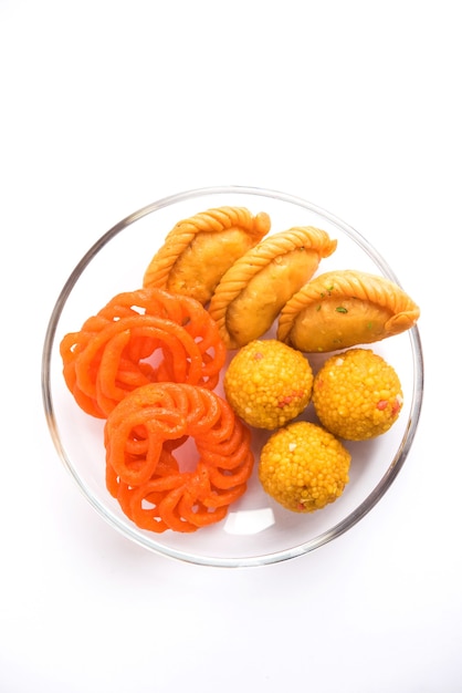 Indian sweet Jalebi or Imarti, Laddu and Gujiya served together over white background or with gifts. Selective focus