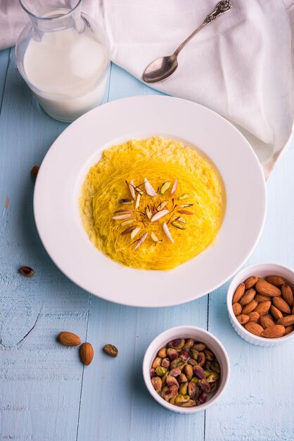 Indian sweet kesar sutarfeni or sutar feni or firni or seviyan or laccha, shredded, flaky-rice-flour roasted in ghee, blended with melted sugar to form a cotton candy, with pistachio and almonds