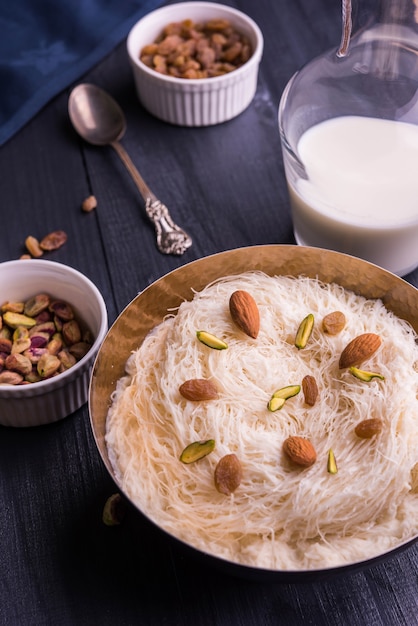 Indian sweet sutarfeni or sutar feni or firni or seviyan or laccha, shredded, flaky-rice-flour roasted in ghee, blended with melted sugar to form a cotton candy, topped with pistachio and almonds