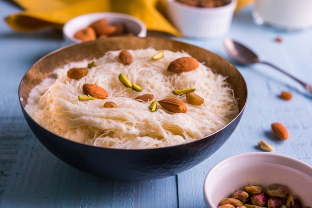 Indian sweet sutarfeni or sutar feni or firni or seviyan or laccha, shredded, flaky-rice-flour roasted in ghee, blended with melted sugar to form a cotton candy, topped with pistachio and almonds