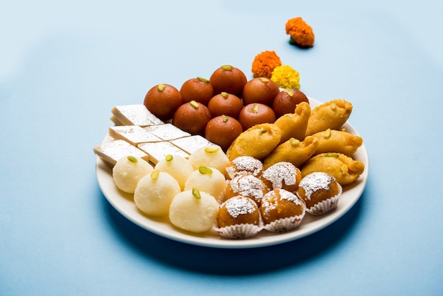 Indian sweets in a plate includes Gulab Jamun, Rasgulla, kaju katli, morichoor or Bundi Laddu, Gujiya or Karanji for diwali celebration