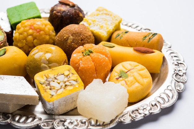 Indian sweets served in silver or wooden plate. variety of Peda, burfi, laddu in decorative plate, selective focus