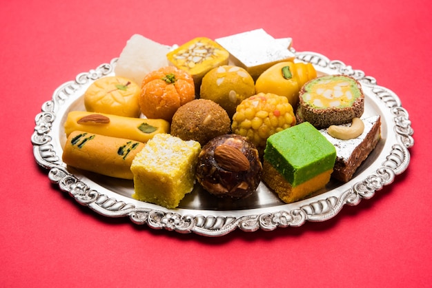 Индийские сладости подают в серебряной или деревянной тарелке. разнообразие Педа, бурфи, ладду в декоративной тарелке, выборочный фокус