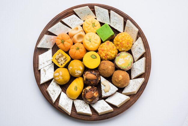 銀または木の板で出されるインドのお菓子。さまざまなペダー、ブルフィ、装飾プレートのラドゥー、セレクティブフォーカス